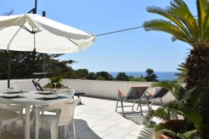a patio with a table and chairs and an umbrella at La terrazza sul mare - Marina di Novaglie in Alessano