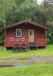 a red cabin with two benches in front of it at Romsdalseggen Camping in Isfjorden