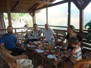 un grupo de personas sentadas alrededor de una mesa comiendo comida en Casa Ana, en Biertan