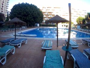 - une piscine avec des chaises longues et des parasols à côté d'un bâtiment dans l'établissement Aguila 110, à Benalmádena