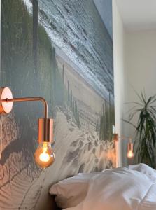 Groede B&B في غرويدي: غرفة نوم فيها لوحة على الشاطئ ومصباح