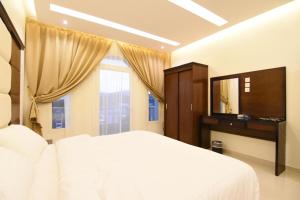 a bedroom with a white bed and a large window at Golden White Hotel in Taif