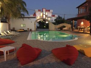 a swimming pool with red pillows in front of a building at Hotel Rainbow Resort in Marsala
