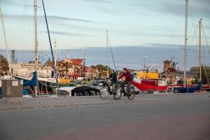 zwei Personen, die in einem Yachthafen mit Booten Fahrrad fahren in der Unterkunft Apartament MORSKA PRZYSTAŃ in Ustka