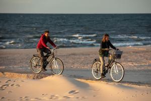 zwei Personen fahren Fahrrad am Strand in der Unterkunft Apartament MORSKA PRZYSTAŃ in Ustka