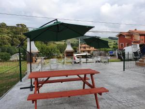 una mesa de picnic con una sombrilla en el patio en BIULES - LA COLINA, en Arnuero