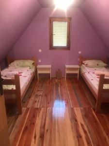 Duas camas num quarto com paredes roxas e pisos em madeira em Apartment Anica em Mokra Gora