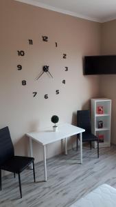 una mesa blanca con sillas y un reloj en la pared en CentRoom Apartman, en Sátoraljaújhely