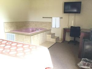 a hotel room with a tub and a bed and a television at Super 8 by Wyndham Imlay City in Imlay City +29 photos
