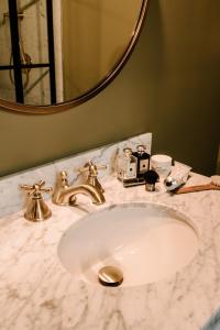 La salle de bains est pourvue d'un lavabo avec un robinet en or et un miroir. dans l'établissement Rosemount Inn, à Kingston