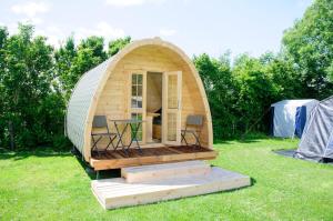 une tente en forme de dôme avec une table et des chaises dans l'herbe dans l'établissement Minicamping Aan de Waterspiegel, à Aagtekerke