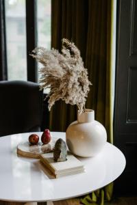 un vase blanc sur une table avec des livres et des pommes dans l'établissement Rosemount Inn, à Kingston