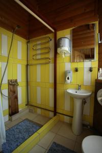 a yellow bathroom with a sink and a shower at Vila Pas Justiną in Palanga