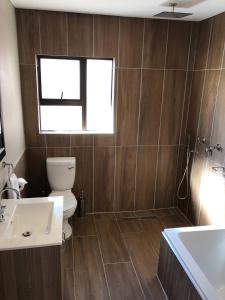 baño con aseo y lavabo y ventana en Ginger Barn, en Pretoria