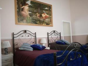 a bedroom with two beds and a painting on the wall at La dimora del giurista in Rossano