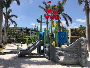 a playground with a slide in the sand with palm trees at FULL TIME LIC MGR - MODERN OCEANFRONT CONDO! BEAUTIFUL OCEAN VIEWS! BEACH RESORT! 2 KING BEDs! in Key Largo