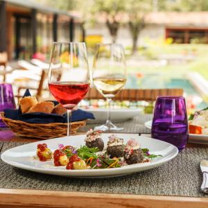 a table with a plate of food and glasses of wine at Sol y Luna - Relais & Chateaux in Urubamba