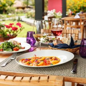 a table with two plates of food and glasses of wine at Sol y Luna - Relais & Chateaux in Urubamba
