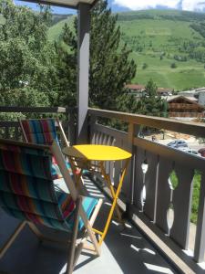 un patio con 2 sillas y una mesa en el balcón en appartement les deux alpes, en Les Deux Alpes