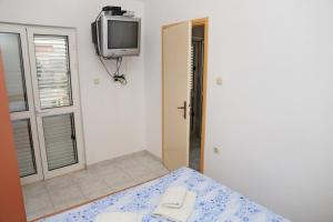 a room with a table and a tv on the wall at Apartments Katica in Lumbarda