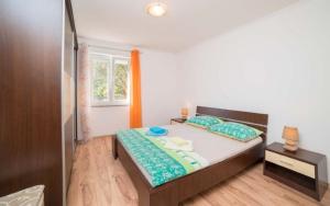 - une chambre avec un grand lit et une fenêtre dans l'établissement Apartmani Slavica, à Rab