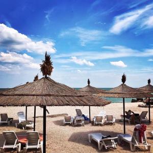 a group of chairs and umbrellas on a beach at Grand Victoria Hotel in Kyrylivka