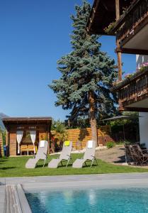 a group of white lounge chairs next to a pool at Alpenresidenz Maria in Silandro