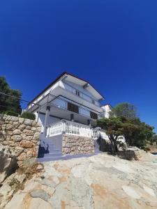 une maison blanche au-dessus d'un mur de roche dans l'établissement Apartmani Mila, à Starigrad-Paklenica