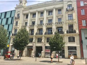 een groot wit gebouw met mensen die ervoor lopen bij Best Place and Comfort Apartments in Brno