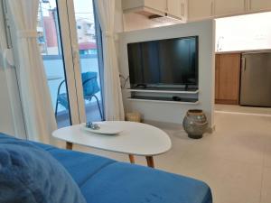 a living room with a couch and a table and a tv at Personal Holiday Homes in Rethymno Town