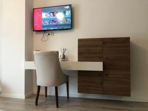 a desk with a chair and a tv on a wall at Hotel Dardani in Mitrovicë