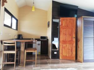 uma pequena cozinha com uma mesa de madeira e uma porta em Cabañas Bambú em San Vito