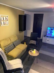 uma sala de estar com um sofá e uma televisão em Lux Apartament em Zalău