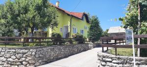 Casa amarilla y verde con pared de piedra en Rooms Jure Sabljak, en Grabovac