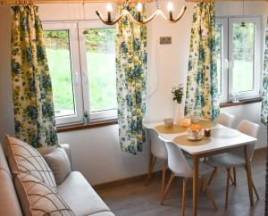 a dining room with a table and chairs and windows at Osada Zawóz domki z balią jacuzzi i sauną nad Jeziorem Solińskim in Zawóz