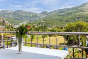 a vase with flowers on a table on a balcony at Hotel Savojo in Petrovac na Moru
