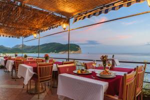 a restaurant with tables and chairs and a view of the ocean at Hotel Savojo in Petrovac na Moru
