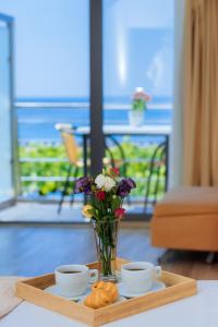 a tray with two cups and a vase with flowers and croissants at Hotel Savojo in Petrovac na Moru