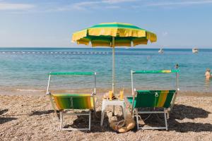 two chairs and an umbrella on a beach at Hotel Savojo in Petrovac na Moru
