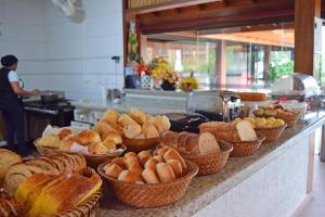 a counter with baskets of bread and pastries on it at Pousada Mais Bella in Ilhabela