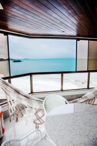 una mesa y sillas frente a una gran ventana en Apto Boutique Baln Camboriu frente mar pe na areia fantastica e exuberante vista mar, en Balneário Camboriú