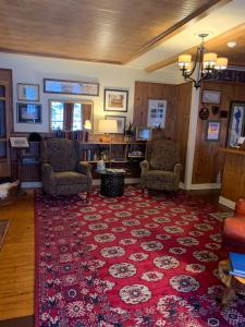 a living room with a red rug and two chairs at Waybury Inn in East Middlebury