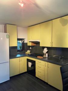 a kitchen with yellow cabinets and a white refrigerator at Lux Apartament in Zalău