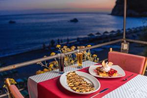 two plates of food on a table with a view of the ocean at Hotel Savojo in Petrovac na Moru