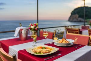 a table with two plates of food and wine glasses at Hotel Savojo in Petrovac na Moru