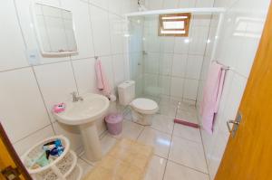 a white bathroom with a sink and a toilet at Chalés da Sinhá in Penha +24 photos