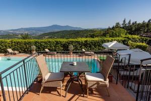 Si Montalcino Hotel في مونتالشينو: فناء مع طاولة وكراسي بجوار حمام سباحة