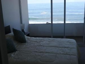 Boulevard del Mar Iquique ,Tierra de Campiones في إكيكي: غرفة نوم مع سرير وإطلالة على المحيط
