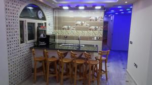 a kitchen with a bar with wooden stools at Al-Madina Tower Apartments in Marsa Matruh