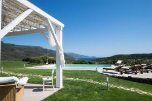 uma pérgola branca com cadeiras e uma piscina em Villa Dama luxury em Alghero